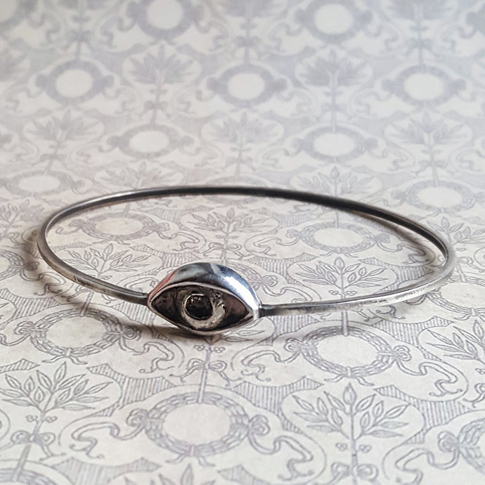 Thin silver bangle with an esoteric symbol, a hand carved eye. 