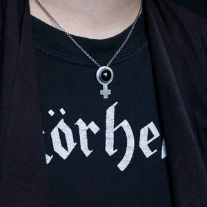 Feminist symbol necklace in silver, with a round onyx. Shown on a person wearing black clothes.