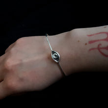 Load image into Gallery viewer, Thin silver bangle with an esoteric symbol, a hand carved eye. Shown on a woman&#39;s wrist