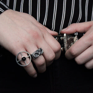 Square signet silver ring with a snake in the shape of an infinity ouroboros on top. Worn on woman's ring finger.